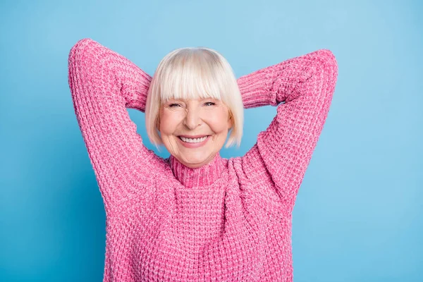 Zdjęcie portret uśmiechniętej starszej pani z dwiema rękami za głową robi przerwę na pastelowym niebieskim tle — Zdjęcie stockowe