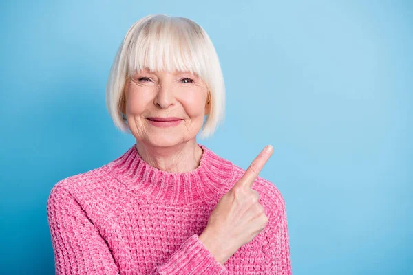 Foto portrét šťastné staré ženy ukazující prstem na prázdné místo izolované na pastelově modré barevné pozadí — Stock fotografie