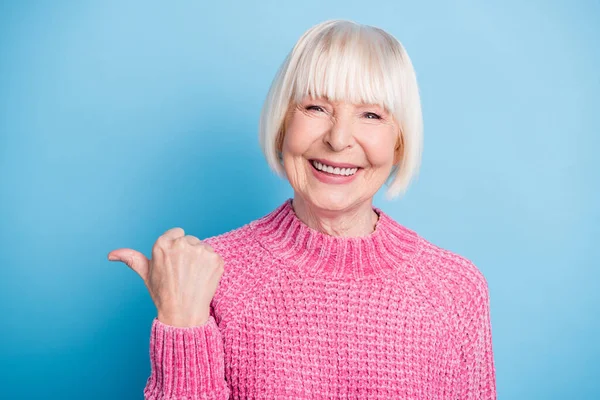 Foto portrét starší ženy ukazující palec na prázdný prostor s úsměvem izolované na pastelově modré barevné pozadí — Stock fotografie