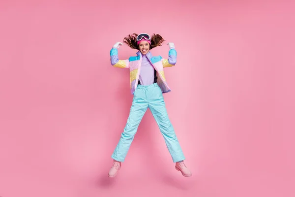 Πλήρες μήκος προφίλ του αξιολάτρευτο funky κυρία snowboarder φορούν πολύχρωμο παλτό eyewear άλμα απομονωμένο ροζ χρώμα φόντο — Φωτογραφία Αρχείου