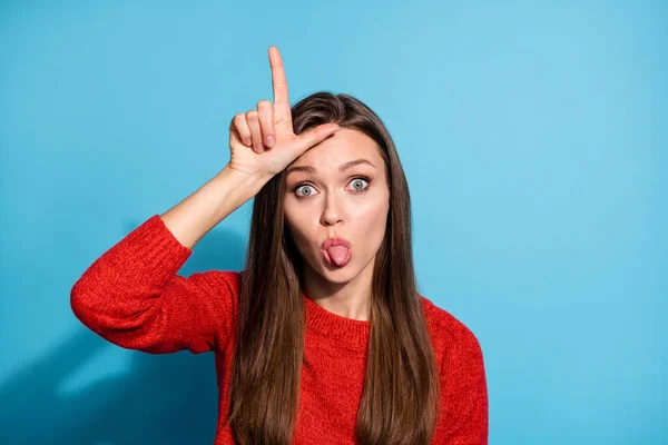 Lady showing loser gesture on forehead teasing bully group mate stick tongue wear red sweater isolated blue color background