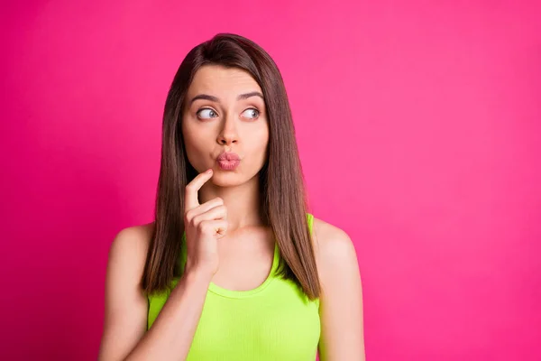 Foto van mooie grappige meisje vinger gezicht lippen kijken kant lege ruimte dragen groene singlet geïsoleerde heldere roze kleur achtergrond — Stockfoto