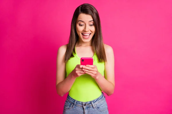 Foto de encantadora señora sorprendida mantenga teléfono inteligente boca abierta desgaste soltera verde aislado vívido fondo de color rosa — Foto de Stock