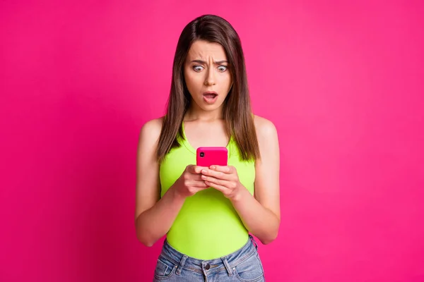 Foto von verwirrt verängstigt junge Mädchen halten Smartphone verwirrt aussehen tragen grüne Top isoliert helle rosa Farbe Hintergrund — Stockfoto