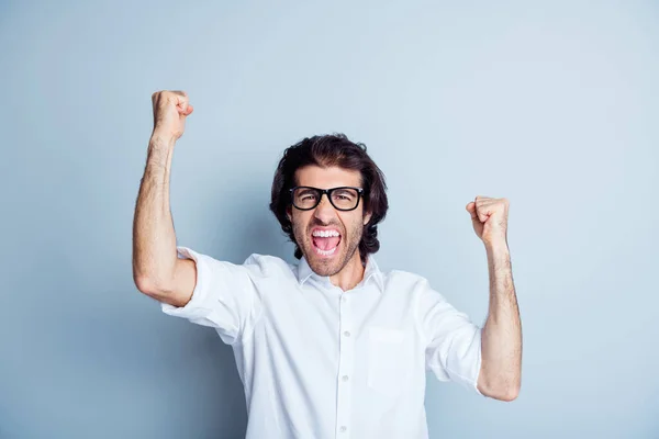 Foto de jovem animado homem feliz sorriso comemorar vitória vitória conquista grito punhos mãos isoladas sobre fundo de cor cinza — Fotografia de Stock