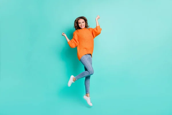 Фотографія повного розміру молодої щасливої позитивної збудженої дівчини, що стрибає у переможному одязі помаранчевого пуловеру ізольовано на кольоровому фоні — стокове фото
