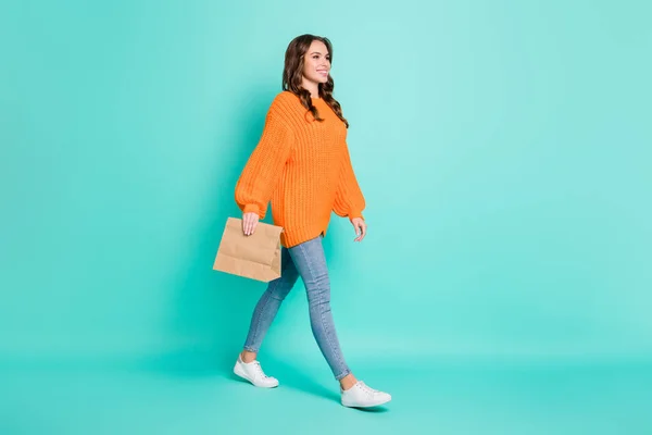 Foto lateral de perfil de tamanho completo da jovem linda menina sorridente ir a pé com saco de papel na mão isolado no fundo cor teal — Fotografia de Stock