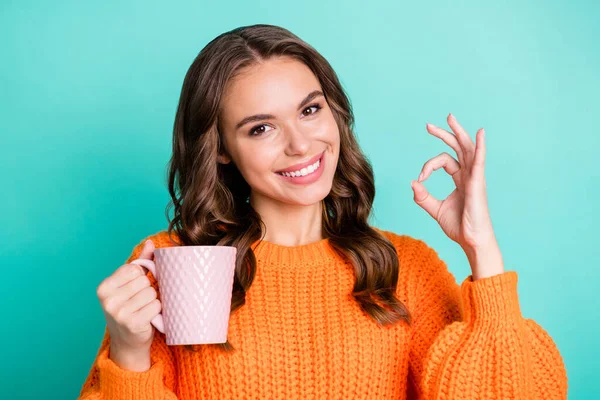 Foto de chica alegre joven sonrisa feliz mostrar consejo signo okey elegir taza de café aislado sobre fondo de color turquesa — Foto de Stock