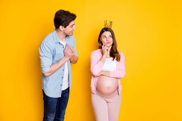 Foto do jovem casal stand mulher grávida acho que usar coroa pano casual isolado no fundo amarelo — Fotografia de Stock