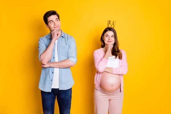 Foto de jovens pensam casal stand olhar espaço vazio mulher grávida usar coroa pano casual isolado no fundo amarelo — Fotografia de Stock