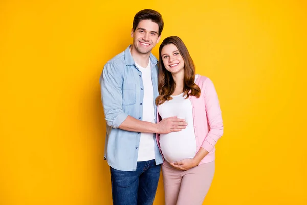 Foto de belo casal atraente esperando criança. Pai mamãe abraçando barriga isolado cor amarela fundo — Fotografia de Stock