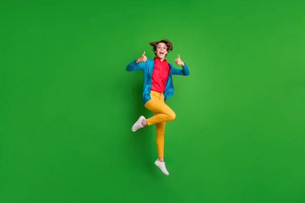 Фотографія повного розміру тіла веселої дівчини, що стрибає високо, показуючи як жест великого пальця ізольовано на яскраво-зеленому кольоровому фоні — стокове фото