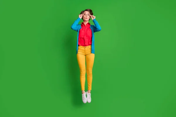 Фотографія повного розміру тіла враженої жінки-студентки, що стрибає, торкаючись окулярів, ізольованих на яскраво-зеленому кольоровому фоні — стокове фото