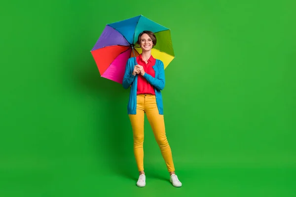 Kısa saçlı, renkli şemsiyeli, parlak yeşil arka planda izole sonbahar kıyafetleri giyen bir kızın boy boy boy fotoğrafı. — Stok fotoğraf