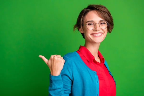 Foto portret van vrolijke vrouwelijke student wijzend naar lege ruimte in bril geïsoleerd op levendige groene kleur achtergrond — Stockfoto