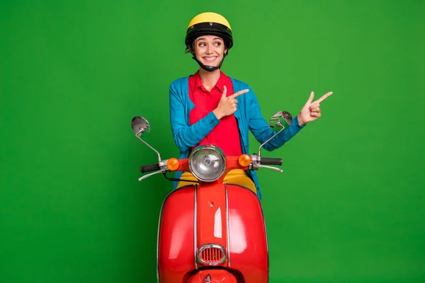 Foto gadis muda yang cantik tersenyum dengan suasana hati yang baik gadis yang ceria lihat titik jari copyspace ride merah moped terisolasi di latar belakang warna hijau — Stok Foto