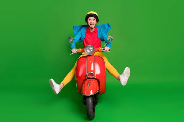 Foto seukuran penuh gadis muda yang menarik dan menarik tersenyum gila positif mengendarai sepeda motor merah yang terisolasi dengan latar belakang berwarna hijau — Stok Foto
