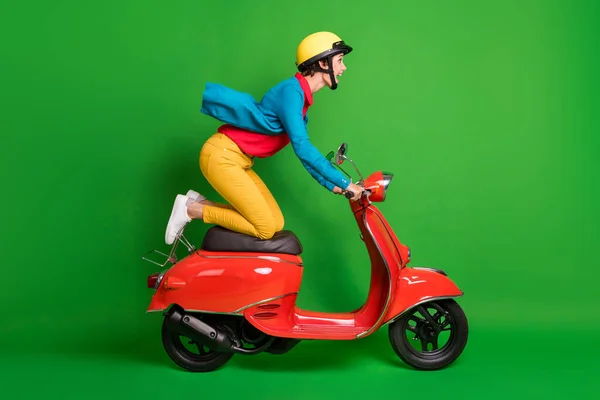 Foto lateral de perfil de tamaño completo de joven feliz loca excitada chica paseo rápido ciclomotor rojo aislado sobre fondo de color verde —  Fotos de Stock