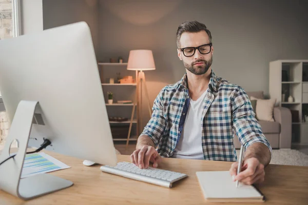 Foto de joven guapo hombre serio concentrado escribir cuaderno plan a hacer lista de trabajo a distancia en interiores —  Fotos de Stock