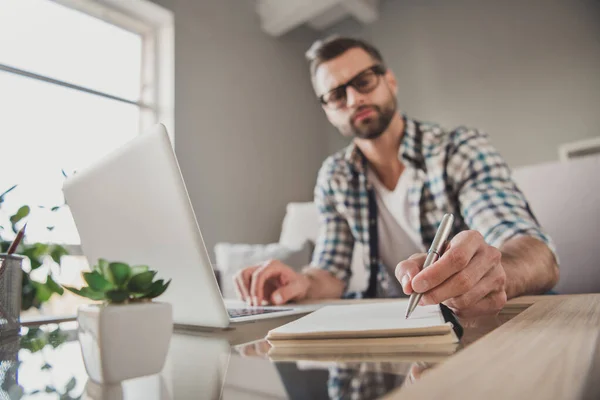 Foto de joven guapo hombre remoto trabajo reloj seminario escribir cuaderno plan para hacer lista seria sentarse sofá interior —  Fotos de Stock