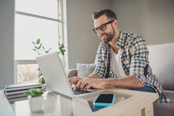 Profilo foto laterale di giovane bell'uomo felice sorriso positivo tipo di chat navigare laptop sedersi divano al coperto distanza di lavoro — Foto Stock