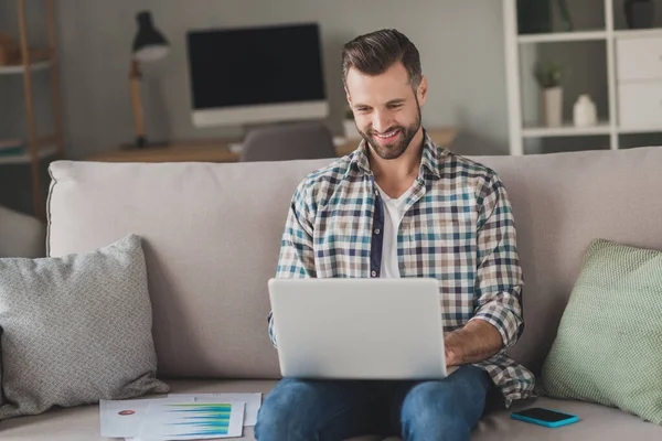 Foto de joven guapo hombre feliz sonrisa positiva sentarse sofá trabajo en casa programador en línea ver webinar portátil — Foto de Stock