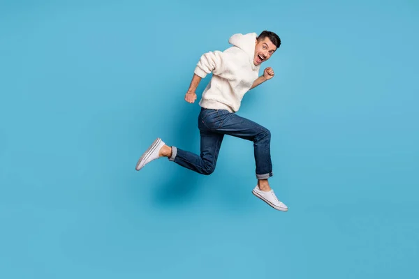 Full size profilo lato foto di giovane felice eccitato sorridente uomo positivo in esecuzione salto isolato su sfondo di colore blu — Foto Stock