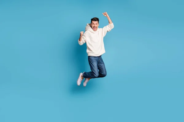 Фотографія повного розміру молодого щасливого позитивного настрою людини, що стрибає кричущі піднімають кулаки в перемозі ізольовані на синьому кольоровому фоні — стокове фото