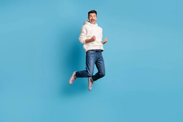Foto ritratto vista corpo pieno di divertente celebrando l'uomo che salta su indossando felpa con cappuccio di lana isolato su sfondo di colore blu pastello — Foto Stock