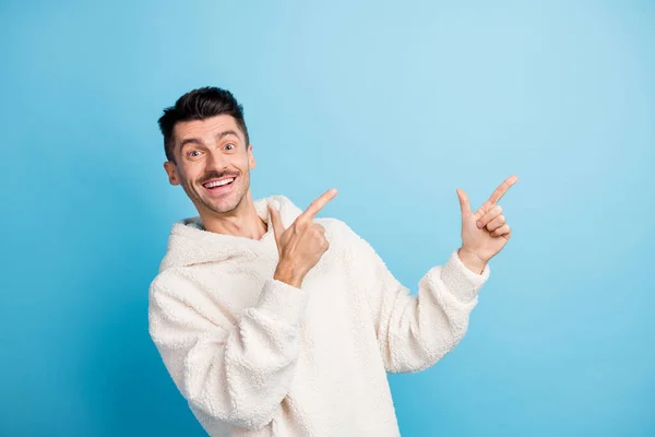 Fotoporträt eines fröhlichen Mannes mit Borsten, die mit zwei Fingern auf Leerstellen zeigen, isoliert auf pastellblauem Hintergrund — Stockfoto