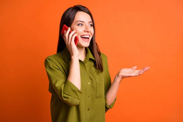Profil fotó funky fiatal lány hold mobiltelefon beszélgetés fényes mosoly viselni zöld ing elszigetelt narancs szín háttér — Stock Fotó