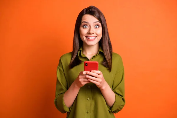 興奮面白い女の子の写真を保持電話光沢のある笑顔は緑のシャツ孤立オレンジの色の背景を着用 — ストック写真
