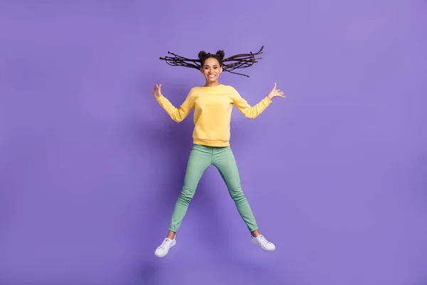 Full size foto van optimistisch mooi meisje springen dragen geel shirt broek sneakers geïsoleerd op lila kleur achtergrond — Stockfoto