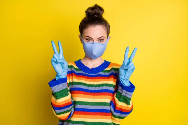 Zdjęcie dziewczyny pokazujące v-sign nosić niebieską maskę rękawiczki z tęczy korony sweter izolowany na jasnożółtym tle — Zdjęcie stockowe