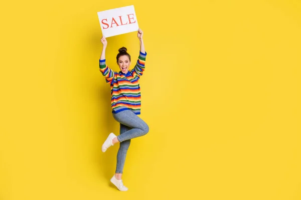 Фотографія збудженої молодої жінки, що тримає продажу карткового слова, піднімає руки ізольовані на блискучому жовтому кольорі — стокове фото