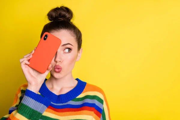 Фото кокетки фанк брюнетка дівчина показує телефон близьке обличчя удар поцілунок носити веселковий светр ізольовано на яскраво-жовтому тлі — стокове фото