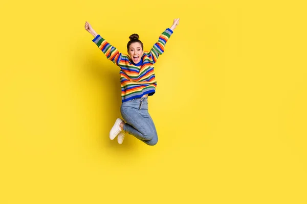 Full body foto van triomfantelijke jonge vrouw spring lucht doel verhogen handen dragen regenboog trui geïsoleerd op gele kleur achtergrond — Stockfoto