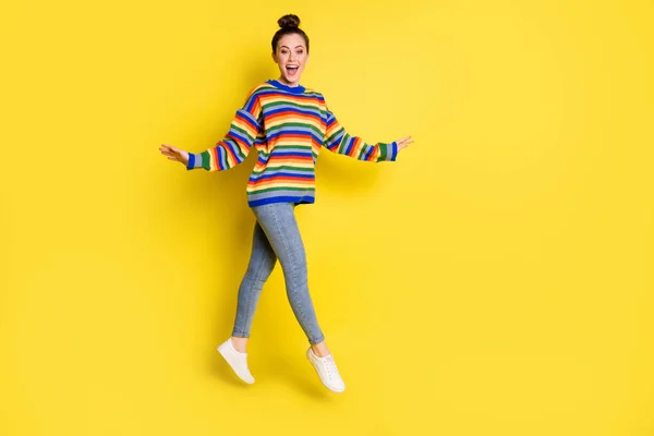 Foto de cuerpo completo de alegre dama encantadora usar suéter de color arco iris saltar aislado sobre fondo de color amarillo — Foto de Stock