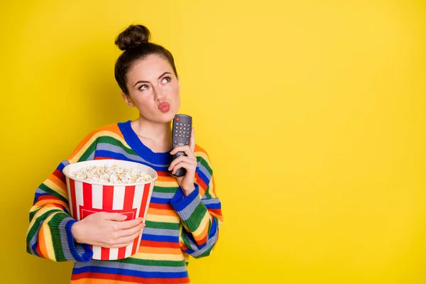 Photo de jeune femme séduisante pense tenir la télécommande manger pop-corn regarder espace vide isolé sur fond de couleur jaune — Photo