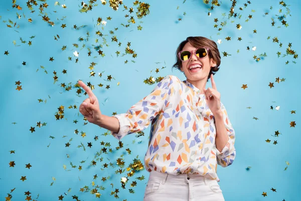 Фото молодой девушки взволнованной весело наслаждаться музыкой танцевальный клуб падения конфетти носить солнцезащитные очки изолированы на синем фоне цвета — стоковое фото