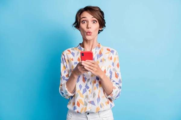 Foto de sorprendido bastante encantadora joven dama celebrar smartphone noticias reacción aislada sobre fondo de color azul —  Fotos de Stock