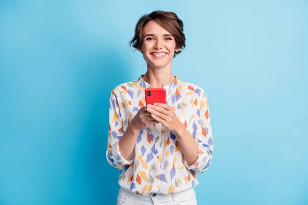 Foto de positiva feliz bonita mujer joven mantenga el buen humor del teléfono inteligente aislado en el fondo de color azul pastel —  Fotos de Stock