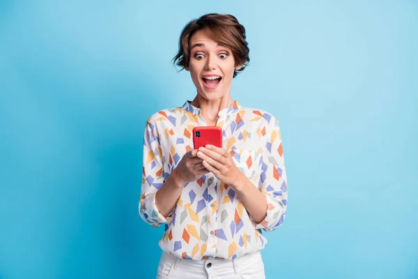 Photo of brunette bob haired girl hold phone wear white print shirt amazed follow isolated on blue color background