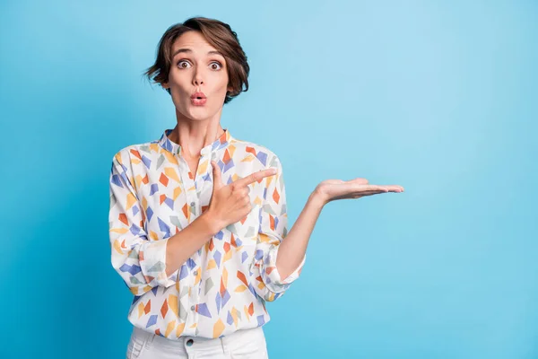 Photo of impressed astonished pretty young lady wear white print shirt hold hand point finger isolated on blue color background — Stock Photo, Image