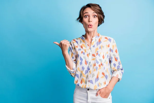 Photo of amazed lovely lady point thumb empty space hold hand pocket wear white print shirt isolated on blue color background — Stock Photo, Image