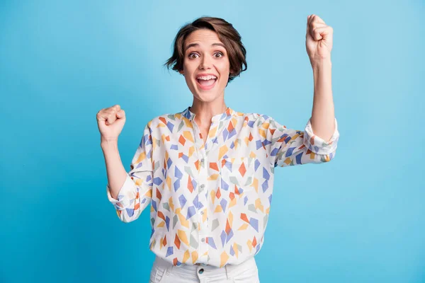 Фото переможниці щасливої веселої молодої жінки-переможниці продовольчого настрою піднімають кулаки ізольовані на пастельному синьому фоні — стокове фото
