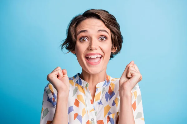 Foto de feliz menina triunfante surpreendido levantar punhos usar camisa de impressão branca isolada no fundo de cor azul — Fotografia de Stock