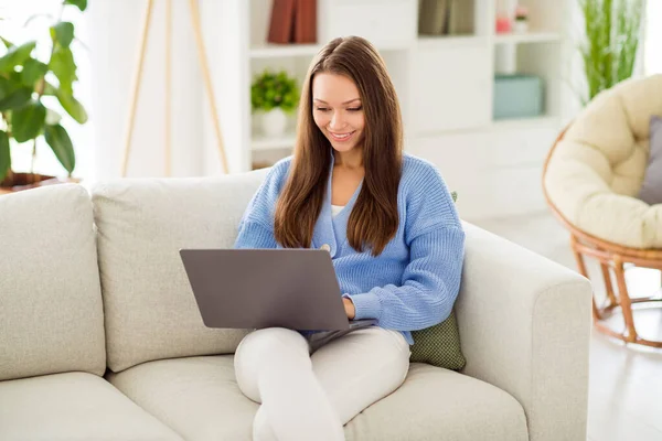 Портрет привлекательной веселой целеустремленной девушки, сидящей на диване с помощью портативного веб-чата, учащейся в светлой квартире — стоковое фото