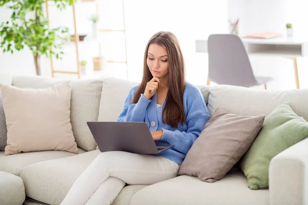 Portrét atraktivní soustředěné zaneprázdněné dívky sedící na pohovce pomocí notebooku psaní pracuje na dálku ve světlém bytě byt vnitřní — Stock fotografie