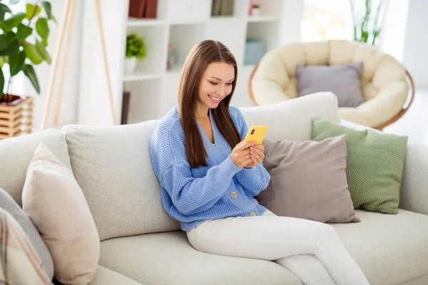 Ritratto di attraente ragazza allegra seduta sul divano utilizzando app dispositivo 5g digitando in appartamento casa piatta luce coperta — Foto Stock